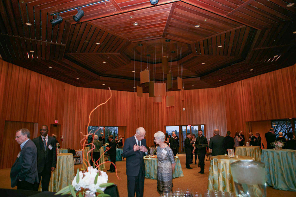 Elaborate wooden room with decorated tables and people mingling