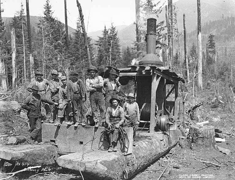 Loggers pose next to the steam donkey machine.